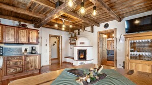 A rustic kitchen with wooden cabinets, a central fireplace, and hanging light fixtures. - Heregger Hütte by Interhome (Dellach)