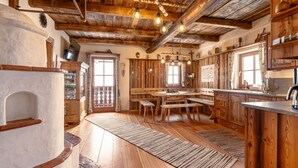 A rustic kitchen with wooden beams, a stone fireplace, and a large window. - Heregger Hütte by Interhome (Dellach)