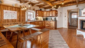 A rustic kitchen with wooden cabinets, a wooden dining table, and a bench. - Heregger Hütte by Interhome (Dellach)