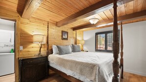 Un dormitorio con paneles de madera, una cama con dosel, una mesita de noche y un ventanal con vistas al exterior.