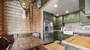 Una cocina rústica con paredes de madera, una mesa de comedor de madera y armarios verdes.