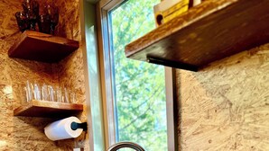 A modern kitchen with a stainless steel sink, a built-in stove, and wooden shelves above the counter. - Pet Friendly Fully Fenced Cozy Casita near Sedona! (Lake Montezuma)