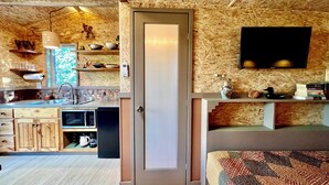 A compact, modern kitchen with wooden cabinetry, a built-in microwave, and a window overlooking greenery. - Pet Friendly Fully Fenced Cozy Casita near Sedona! (Lake Montezuma)