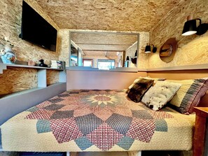 Ein Schlafzimmer mit einem großen Bett, einem Spiegel und einer Holzbalkendecke.