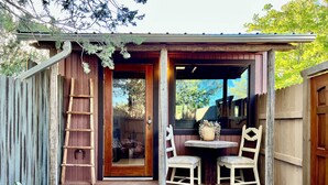 A wooden cabin with a porch, a ladder, two chairs, and a table. - Pet Friendly Fully Fenced Cozy Casita near Sedona! (Lake Montezuma)