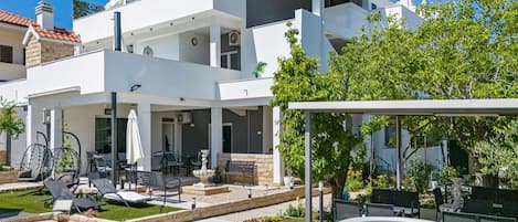 Uma casa moderna de dois andares com varanda coberta, área de estar externa e piscina.