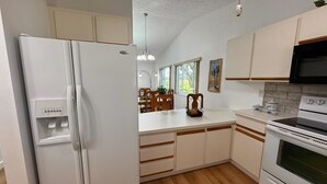 A modern kitchen with white cabinetry, a built-in oven, and a refrigerator.