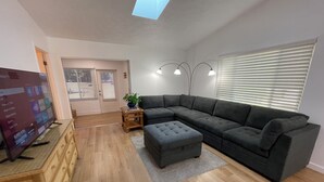 A modern living room with a sectional sofa, a television, and a wooden cabinet.