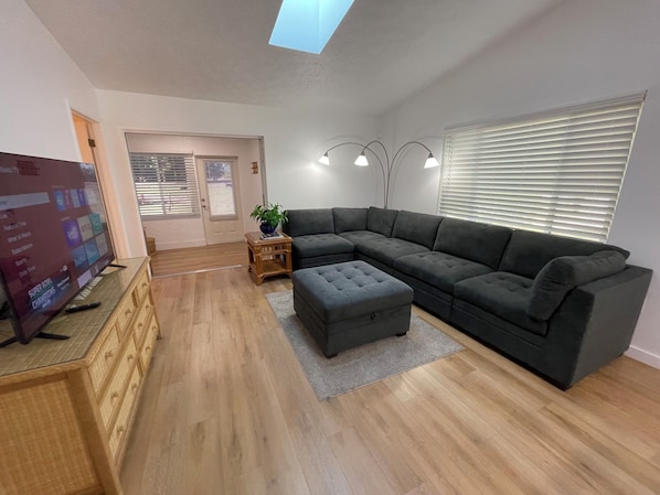 A modern living room with a sectional sofa, a television, and a wooden cabinet.