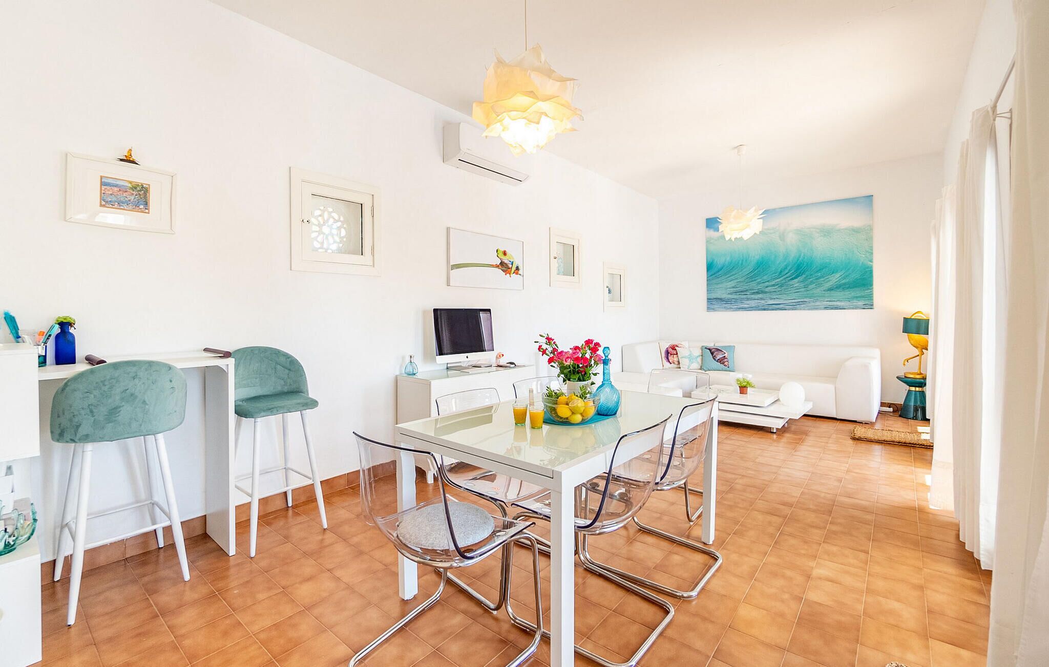 A modern living room with a dining area, featuring a large window, a painting of a wave, and a white sofa.