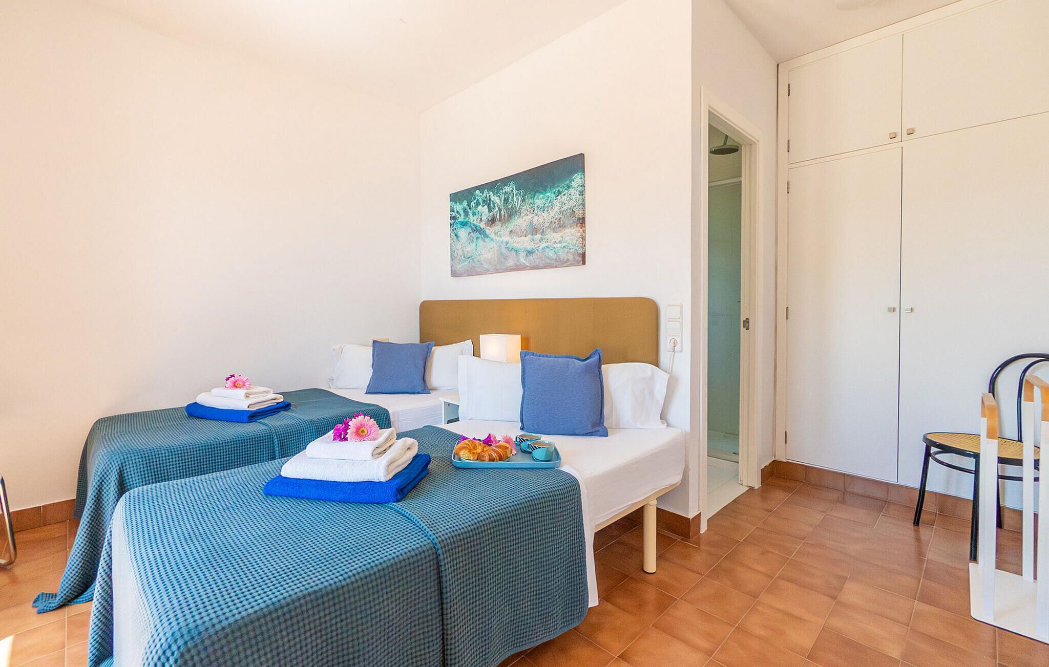Een hotelkamer met twee bedden, een schilderij aan de muur en een stoel.