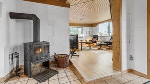 Une pièce chaleureuse avec un poêle à bois, une télévision et un coin salon confortable avec une table et des chaises.
