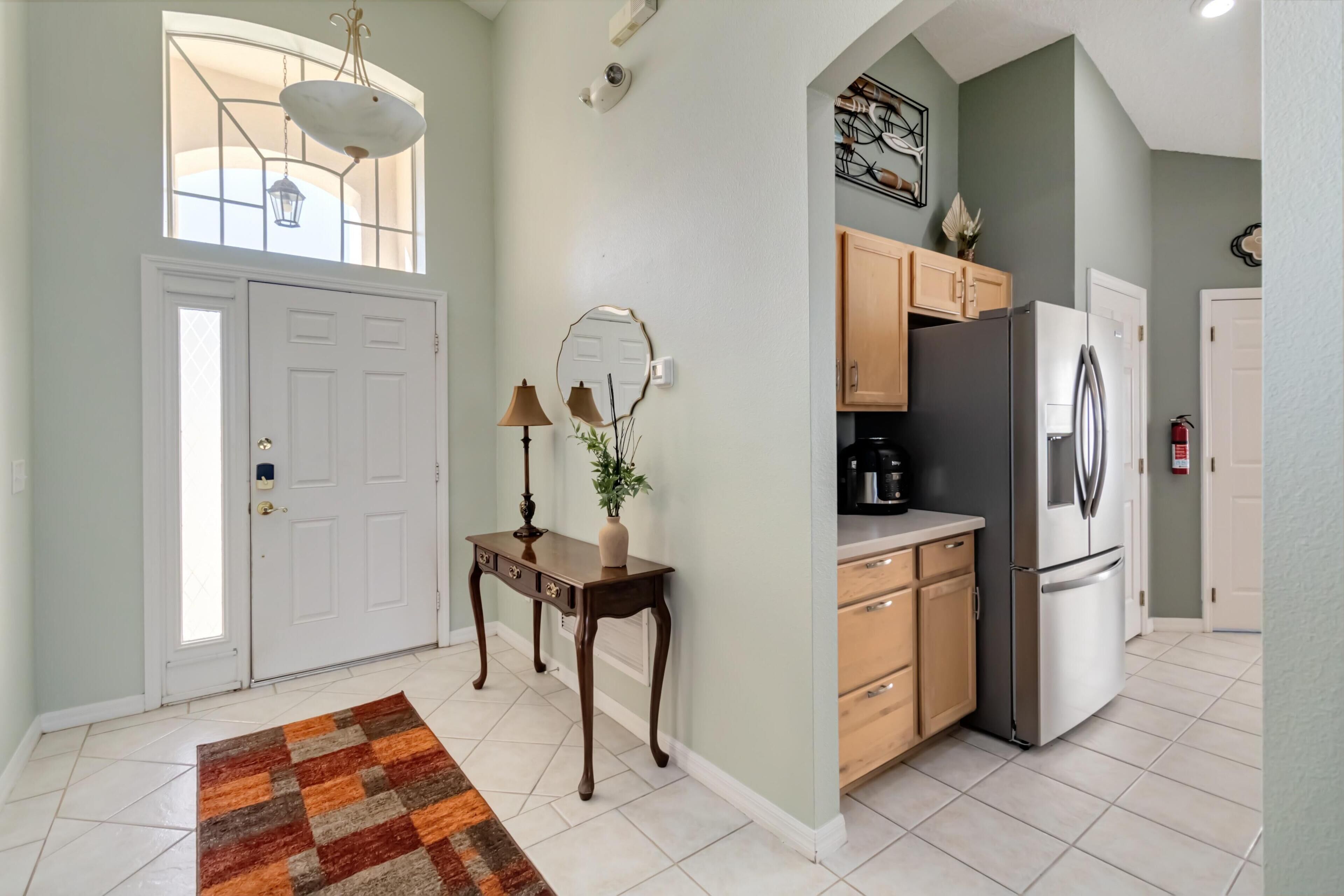 A kitchen with wooden cabinets, a stainless steel refrigerator, and a window above the sink.