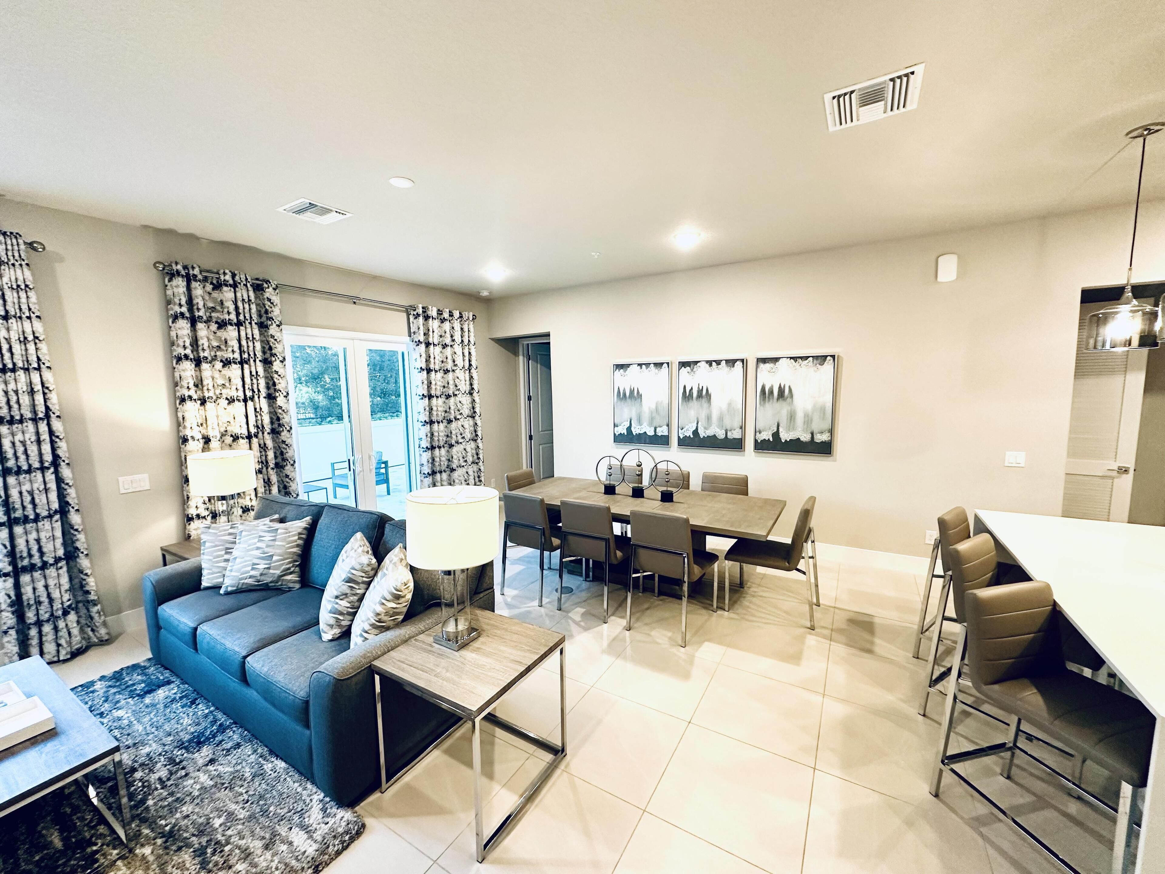 A modern living room with a sofa, coffee table, and dining area with chairs and a table.