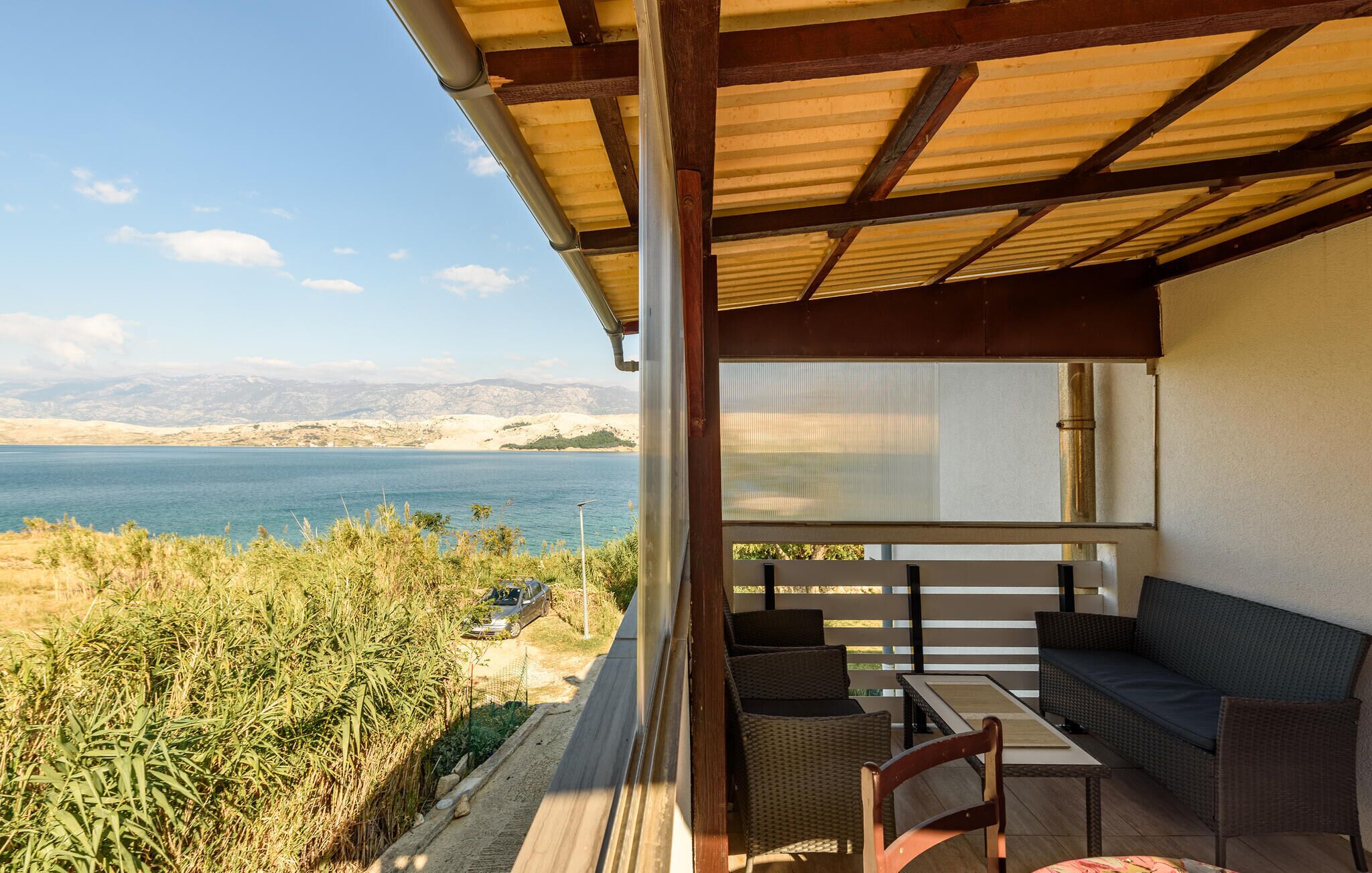A covered outdoor seating area with a view of a lake and mountains.
