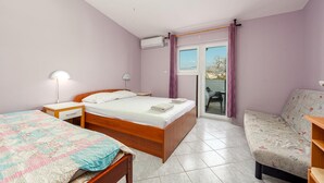 A bedroom with a bed, a desk, a chair, and a balcony with a view. - Amazing apartment in Pag with house sea view (Pag)