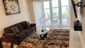 A living room with a brown sofa, a glass coffee table, and a shaggy rug. - 2-bedrooms condo with spectacular Ocean View, WiFi, AC in delightful Montego Bay (Montego Bay)