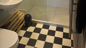 Ein Badezimmer mit Waschbecken, Toilette, Dusche und einem Schachbrettmuster auf dem Boden.