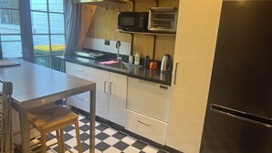 Eine Küche mit einem schwarz-weißen Schachbrettmuster, einem Edelstahl-Kühlschrank, einer Mikrowelle und einem Toasterofen.