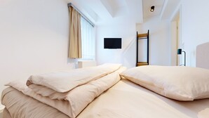 Et moderne hotelværelse med en stor seng, et fladskærms-tv ophængt på væggen og et vindue med gardiner.