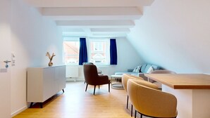 En moderne og lys lejlighed med spiseområde, sofa og et lille bord.