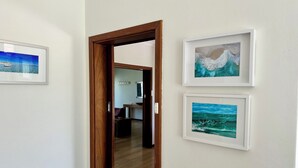 A hallway with a wooden door leading to a room with a dining area and a view of the ocean. - Mermaids Rest Awaits (EMU POINT)