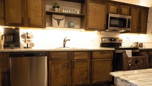 A kitchen with wooden cabinets, a stainless steel dishwasher, a microwave, and a coffee maker. - Cozy studio with queen pullout sofa on scenic working ranch in Fort Worth. (Fort Worth)