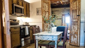A rustic kitchen with wooden cabinets, stainless steel appliances, and a cowhide rug. - Cozy studio with queen pullout sofa on scenic working ranch in Fort Worth. (Fort Worth)
