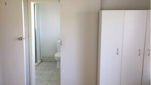 A room with a white wardrobe, a door leading to a bathroom with a toilet and a tiled floor. - An ultra-convenient 2 bed 2 bath unit near CBD with River Derwent&mountain views (Sandy Bay)