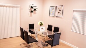 A conference room with a glass table, black chairs, a white vase with flowers, and two framed posters on the wall.