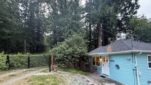 A small blue house with a number 12330 on the door, surrounded by trees and a black gate. - Charming Lake Cottage+Private Dock+AC—Bring your paddles floats & fishing rods! (Sedro-Woolley)