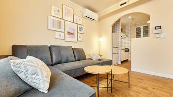 A modern living room with a grey sofa, a round wooden coffee table, and a white decorative pillow.