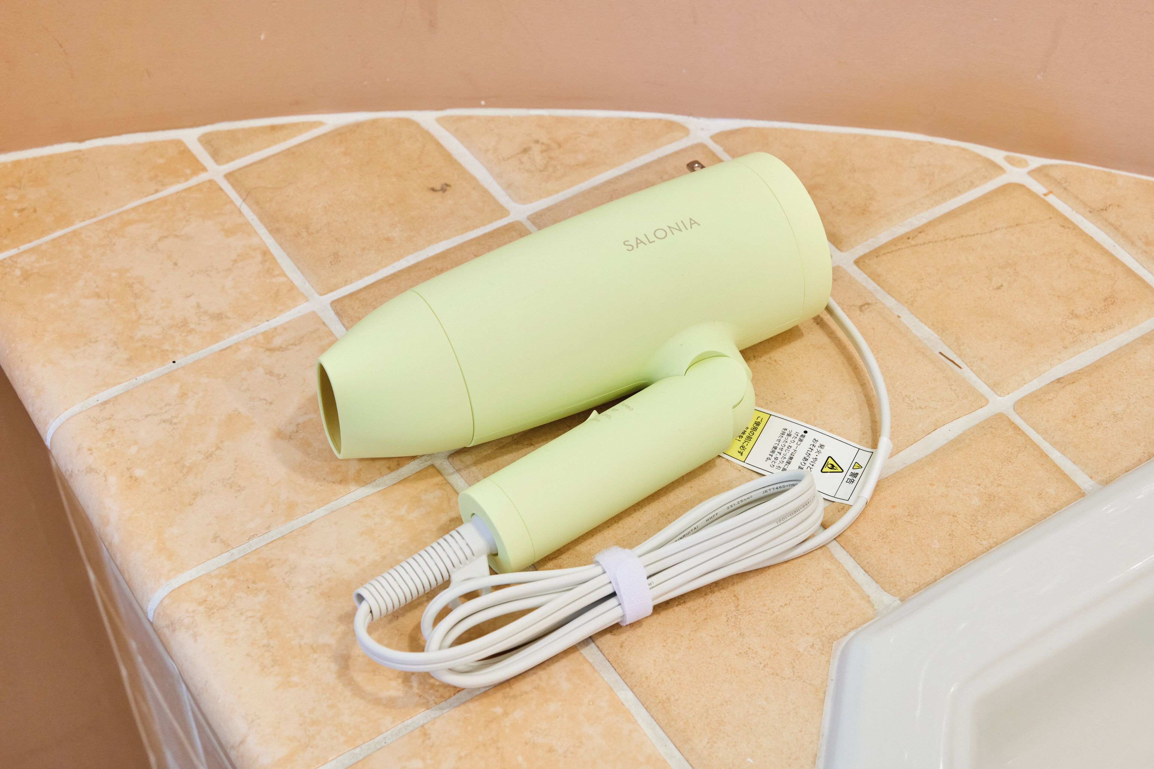 Two light green hair curlers on a tiled surface.