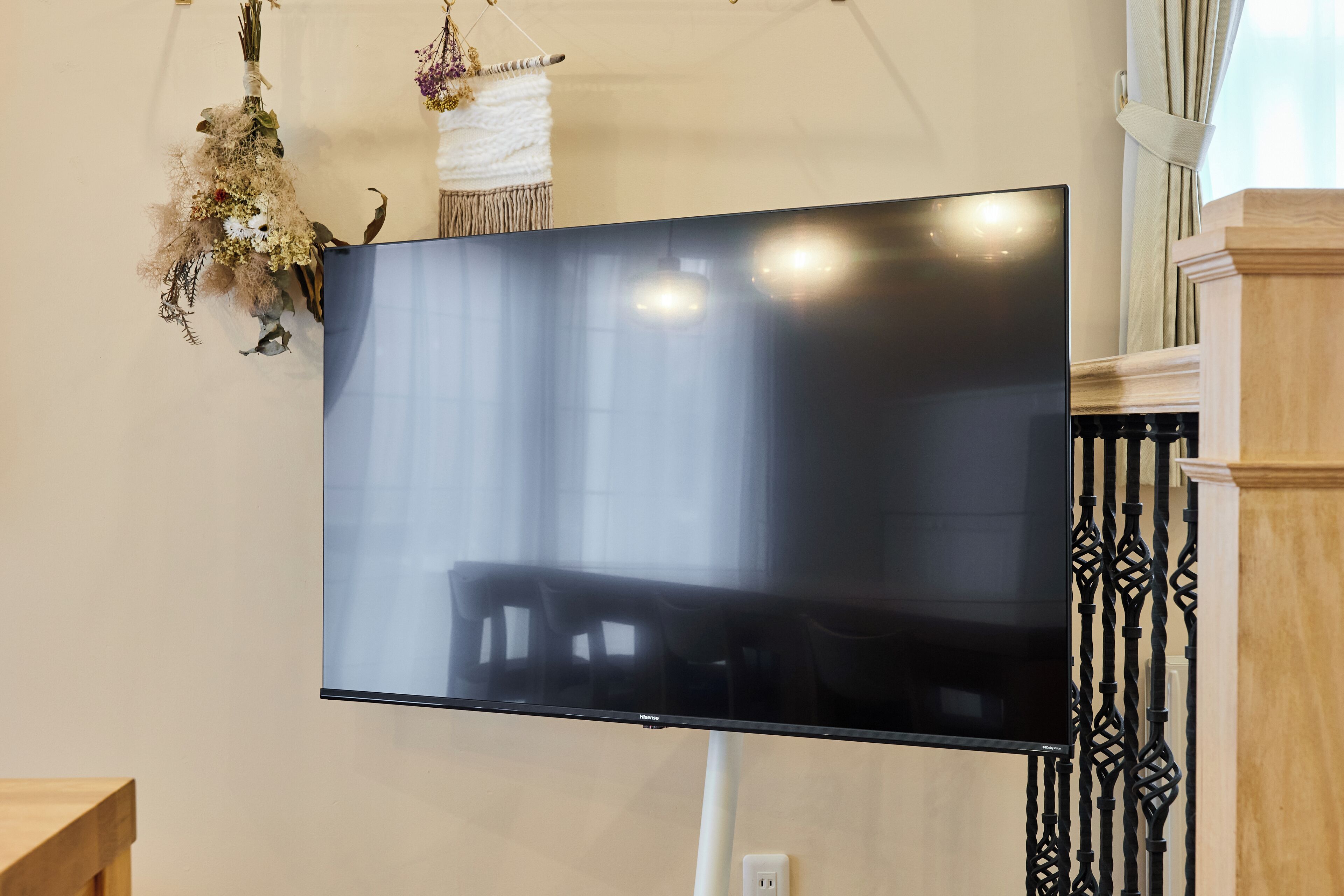 A flat-screen TV mounted on a wall with a white cable running down.