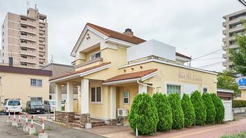 A two-story building with a beige facade, a red-tiled roof, and a sign reading "New MK Living."