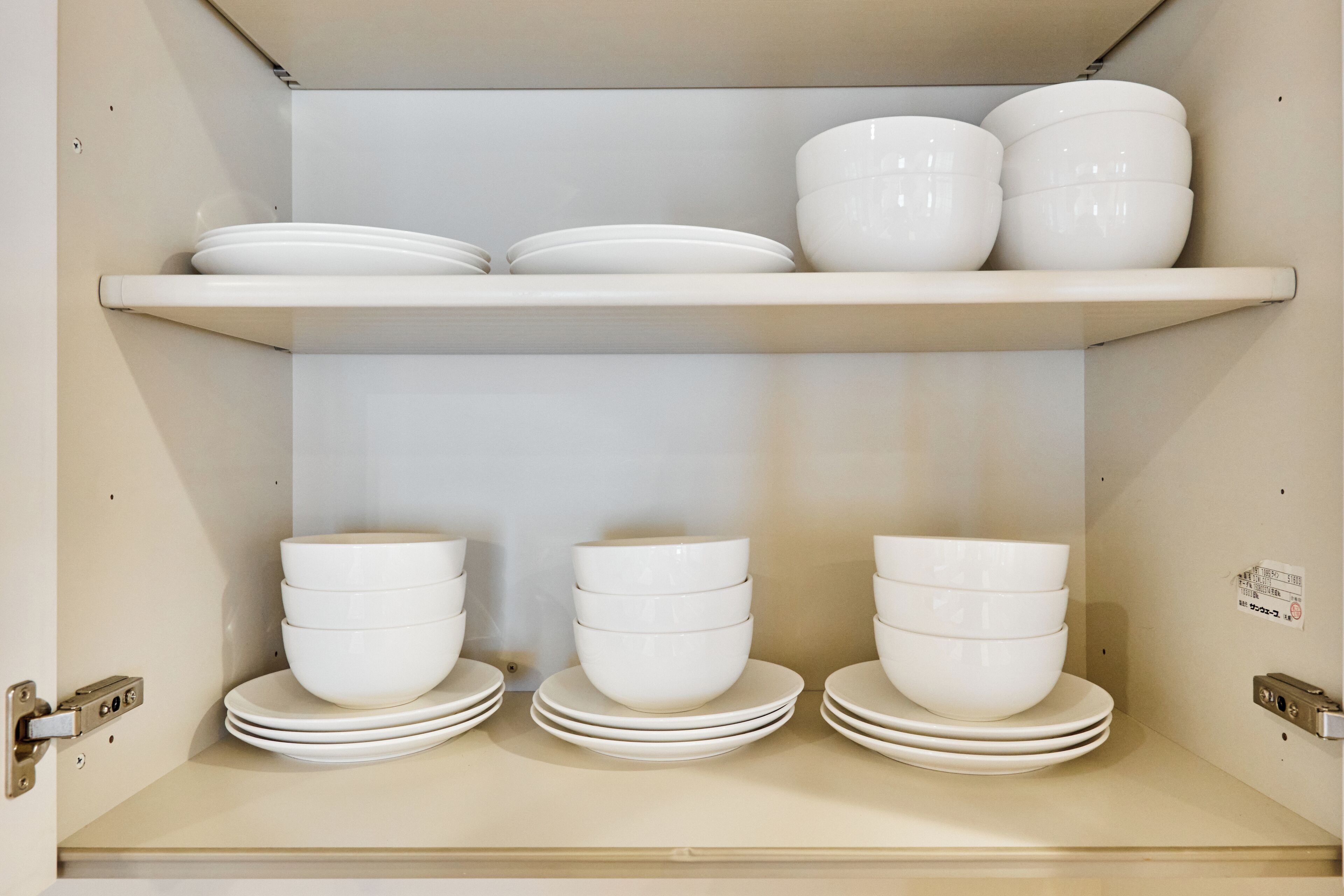 A storage unit with multiple shelves holding white bowls and plates.