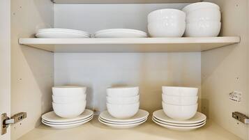 A storage unit with multiple shelves holding white bowls and plates.