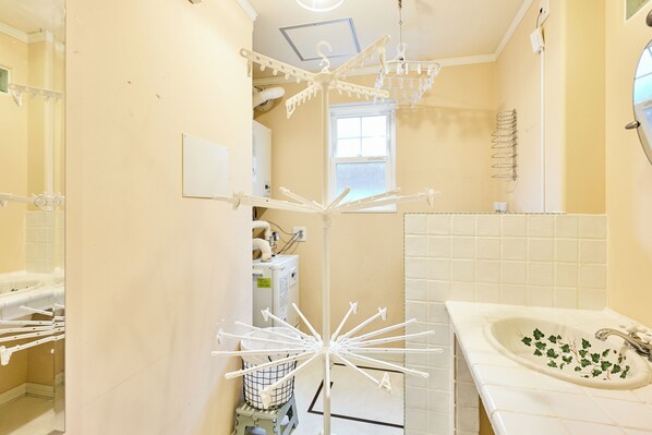 Un bagno con un lavandino bianco, uno specchio e uno stendibiancheria.