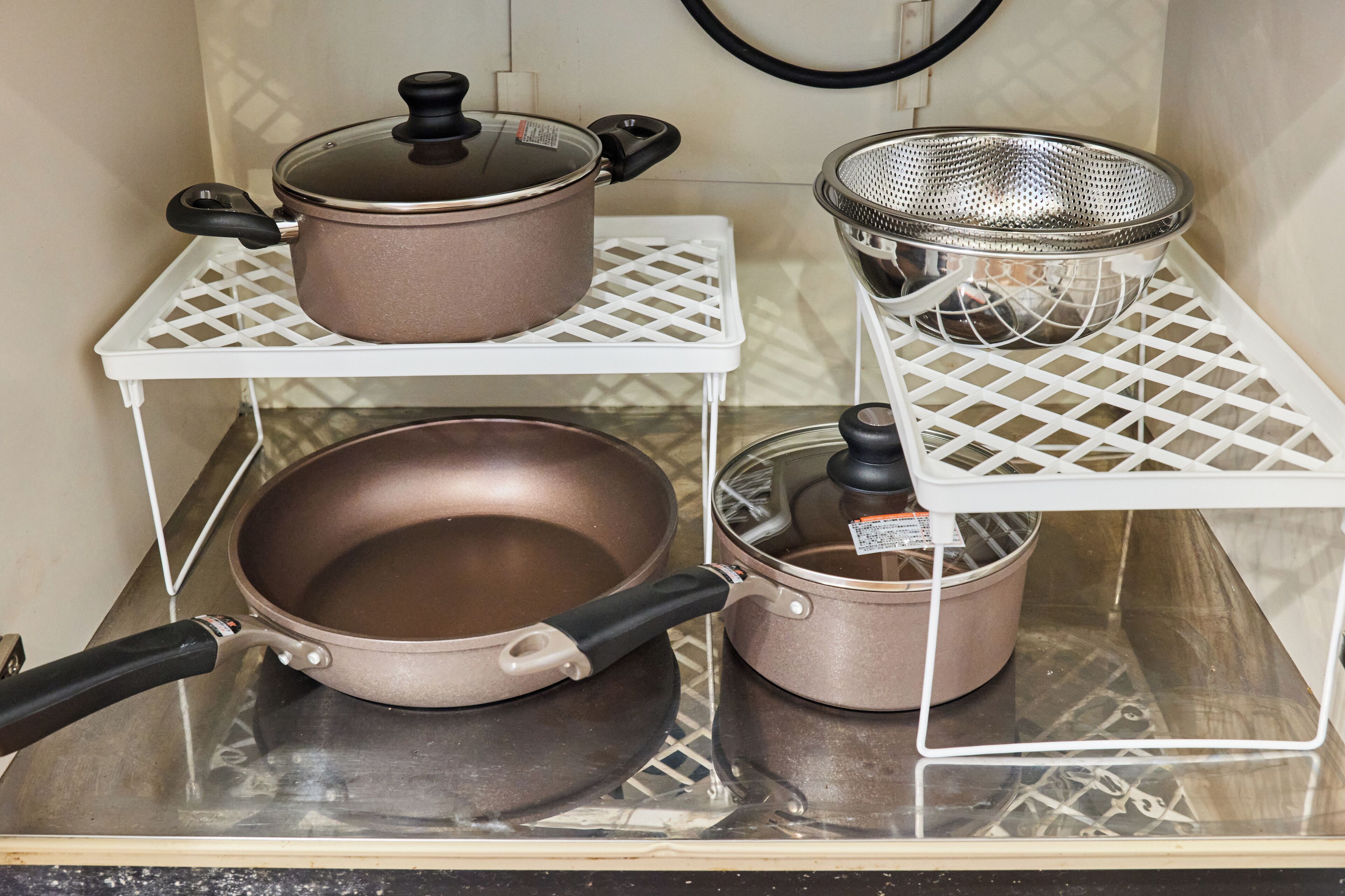 Una cucina con elettrodomestici in acciaio inossidabile e pentole su scaffali bianchi.