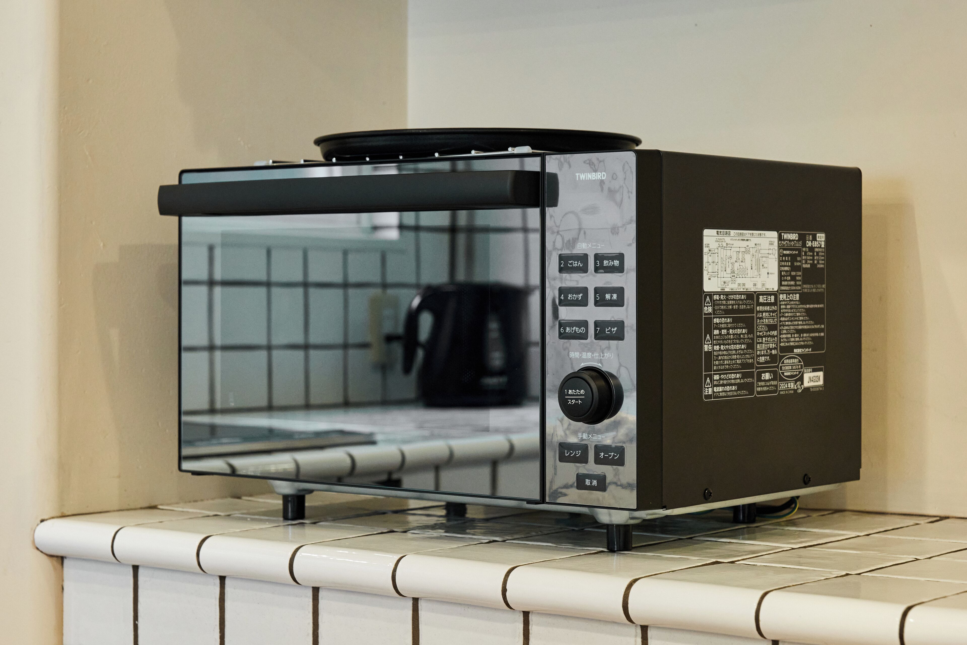 Een keuken met een ingebouwde toaster op een betegeld aanrecht.