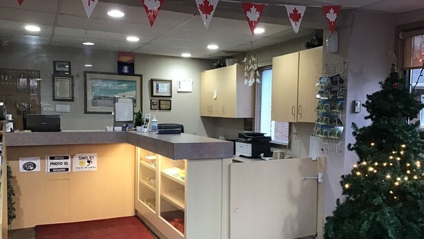 A reception area with a desk, a Christmas tree, and Canadian flags.