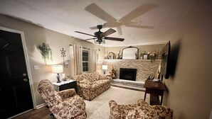 A living room with floral-patterned sofas, a fireplace, and a ceiling fan.