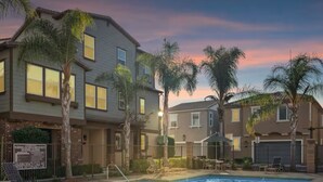 Una zona residencial con piscina, casas y palmeras.