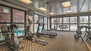 Un gimnasio con cintas de correr, elípticas y equipo de pesas.