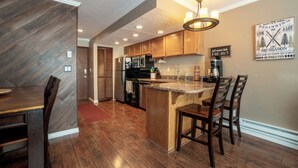 Una cocina moderna con armarios de madera, una isla central y un comedor con sillas.
