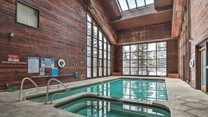 Una piscina interior con paredes de madera y ventanas amplias.