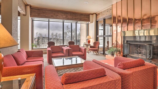 Un salón espacioso con chimenea, ventanas amplias y sofás estampados rojos.