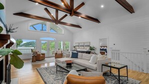 A spacious living room with a large window, a fireplace, and a high ceiling with exposed beams. - 900ft of water frontage: Private Spacious Luxury Waterfront Point @ Smith Lake! (Bremen)