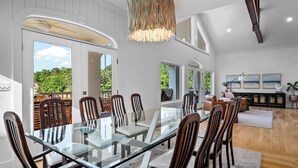 A dining area with a glass table and chairs, a hanging light fixture, and a view of greenery outside. - 900ft of water frontage: Private Spacious Luxury Waterfront Point @ Smith Lake! (Bremen)