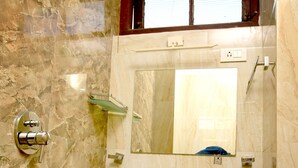A bathroom with a marble wall, a sink, a mirror, and a window above the mirror. - Hotel Mani (Ujjain)